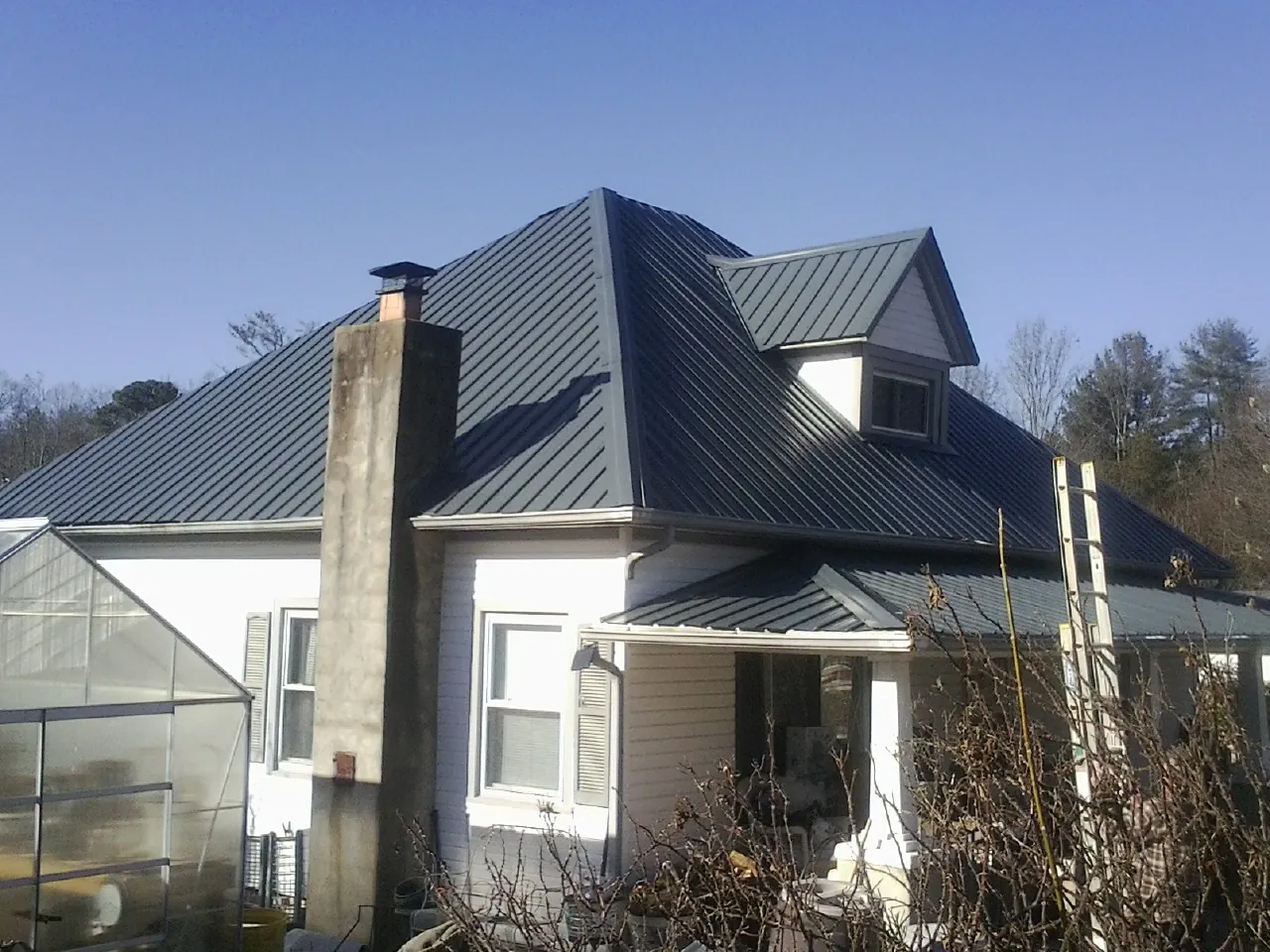 Dark blue standing seam metal roof on a white farmhouse with dormer — Slate & Tile Roof Repair by Roofing Brothers in Oberlin