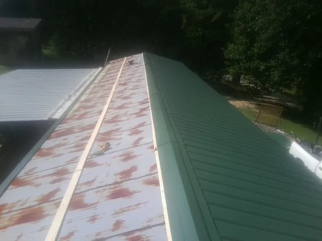 Old rusted panels beside newly installed green metal roofing — Wind Damage Roof Repair by Roofing Brothers in Oberlin