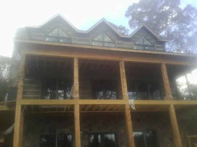 Dormers and porch framing on a large log home under construction — Roof Coating work by our crew in Oberlin