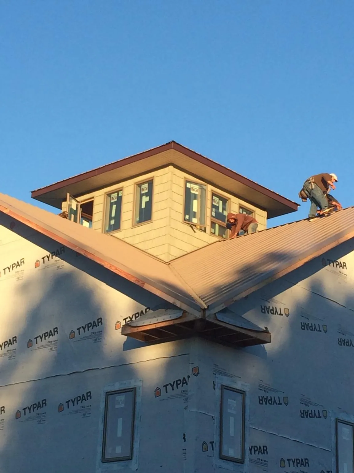 Roofers working around a rooftop cupola on a new metal roof at sunset — Roof Waterproofing in Oberlin by Roofing Brothers